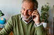 © VALENTINA BARRETO STUDIO/Westend61 - Smiling mature man talking on mobile phone while sitting at home