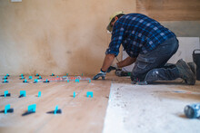 Male Manual Worker Concentrating While Working On Parquet Floor In House