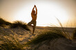 © UWE_UMSTAETTER/Westend61 - Shirtless man practicing tree pose amidst plants at beach against clear sky during sunset