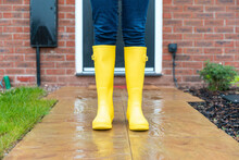 Woman Wearing Rubber Boot Standing In Back Yard During Rainy Season