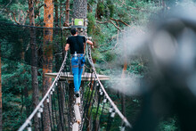 Young Man Crossing Rope Bridge In Adventure Park