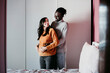 © Eva Blanco/Westend61 - Happy man embracing pregnant woman in bedroom at home
