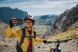 © Photographer: David Molina Grande/Westend61 - Smiling female cyclist taking selfie with mountain bike against mountain, Picos de Europa National Park, Cantabria, Spain