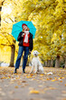 © JAN TEPASS/Westend61 - Teenage girl holding umbrella while standing with pet on road at park