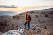 © Rafa Cort√©s/Westend61 - Smiling female hiker looking away while standing on rock mountain during sunset