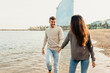 © VALENTINA BARRETO STUDIO/Westend61 - Smiling couple holding hands while walking on water at beach