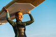 © Ezequiel Gimenez/Westend61 - Mature woman carrying paddleboard on head while standing against blue sky