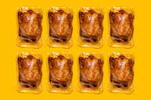 Vacuum Packed Roasted Chickens Arranged In A Row On Yellow Background