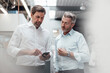 © KNSY/Westend61 - Mature businessmen discussing over smart phone while standing in industry
