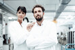 © Westend61 - Confident female scientist with hand on male colleague's shoulder at bright laboratory