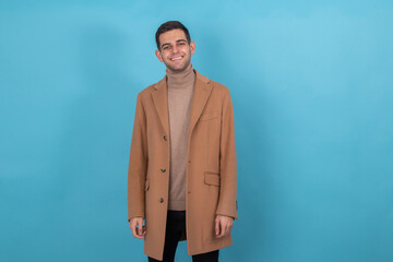 attractive young man in coat isolated on color background