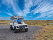 © Albrecht Wei√üer/Westend61 - Happy mid adult man relaxing on hood of off-road vehicle during road trip at Jokulsarlon, Iceland