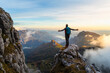 © Westend61 - Pensive hiker with arms outstretched standing on mountain during sunrise at Bergamasque Alps, Italy