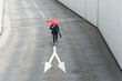 © UWE_UMSTAETTER/Westend61 - Businessman with red umbrella walking on road marking