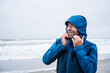 © UWE_UMSTAETTER/Westend61 - Happy mature man in blue raincoat looking away while standing at beach