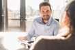 © Uwe Umst√§tter/Westend61 - Smiling businessman working with colleague while sitting at office