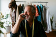 © VALENTINA BARRETO STUDIO/Westend61 - Happy male costume designer looking away while talking on mobile phone at work studio