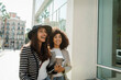 © VALENTINA BARRETO STUDIO/Westend61 - Happy female coworkers standing on street in city during sunny day