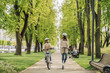 © Hernandez and Sorokina/Westend61 - Girl cycling while mother riding electric scooter on road in city park