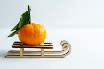 Wall Mural - Tangerine fruit rides on a wooden winter sled. White background. Copy space