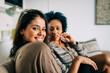 © Alexandra C. Ribeiro/Westend61 - Smiling young woman with friend sitting on sofa at home