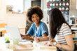 © Giorgio Fochesato/Westend61 - Happy women with laptop studying at table in coffee shop