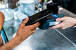 © Giorgio Fochesato/Westend61 - Female customer making contactless payment through smart phone in coffee shop