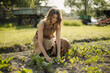 © Gustafsson/Westend61 - Young woman caring for plants in a vegetable patch