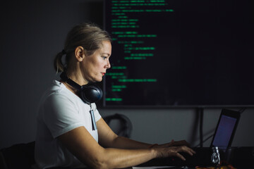 Side view of IT professional working on laptop in office