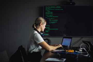 Female IT professional typing on laptop in creative office