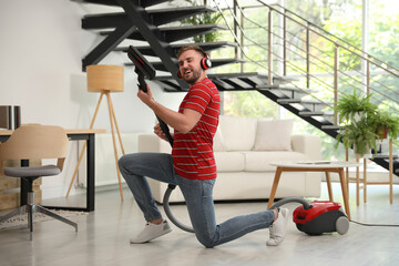 Poster - Young man having fun while vacuuming in living room