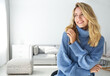 Beautiful young woman wearing warm blue sweater at home. Space for text