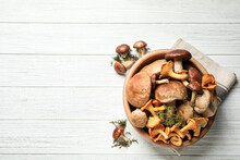 Different Fresh Wild Mushrooms On White Wooden Table, Flat Lay. Space For Text