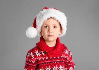 Wall Mural - Cute child in Santa hat on grey background. Christmas celebration