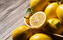Lemons In A Basket And Cut Lemons On A Wooden Background