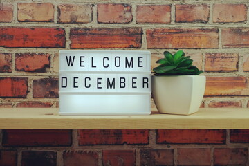 Wall Mural - Welcome December word in light box on wooden shelves background