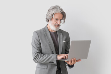 Wall Mural - Portrait of senior businessman with laptop on grey background