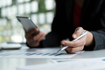 Businessman hand holding pen and pointing at financial paperwork with financial network diagram.