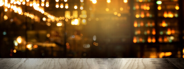 top of black wood table with blur lamp light of club or bar at night party banner background