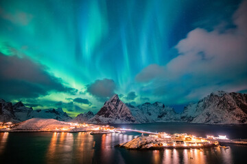 Aurora borealis on the Hamnoy village in Lofoten islands, Norway. Green northern lights above mountains. Night sky with polar lights. Night winter landscape.