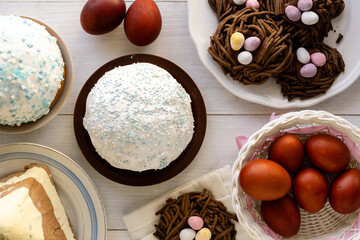 Wall Mural - Traditional easter food. Cakes, nest cookies and colored eggs on wooden table