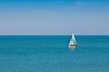 Lonely Man In A Small Sailboat In The Middle Of A Calm Sea - Unrecognizable Man