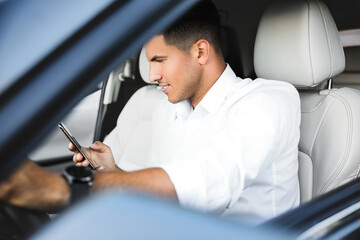 Wall Mural - Handsome man using smartphone while driving his modern car