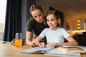 Wall Mural - Beautiful focused military woman doing homework with her daughter at home