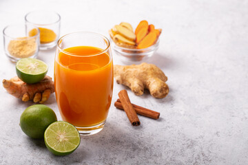 Wall Mural - Healthy drink from turmeric and ginger roots and lime in a glass on white concrete background.