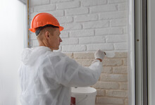 Worker Is Painting A Brick Wall With A Brush.