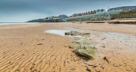 The linear patterns on the sand caused by the outgoing tide, with the Promenade in the background in Whitley Bay, England