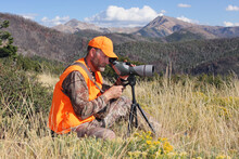 Adult Deer Hunter Looking Through Spotting Scope In Mountains