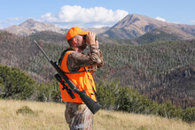 Adult Male Deer Hunter Looking Through Binoculars In Rugged Mountains
