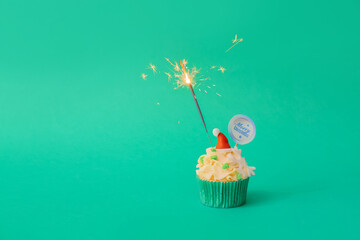 Wall Mural - Tasty Christmas cupcake with sparkler on color background